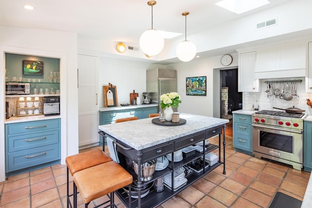 kitchen featuring premium appliances, blue cabinets, decorative backsplash, light countertops, and recessed lighting