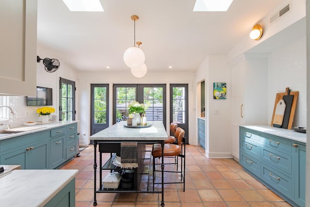 kitchen with a skylight, healthy amount of natural light, light countertops, a sink, and recessed lighting