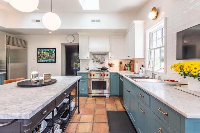 kitchen featuring high end appliances, a sink, white cabinetry, backsplash, and blue cabinetry