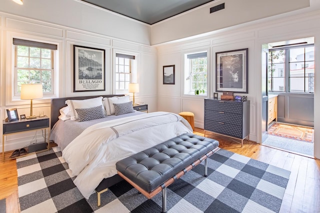 bedroom with wood finished floors, multiple windows, and a decorative wall