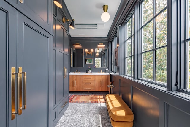 full bathroom with granite tiled floors, double vanity, and a decorative wall