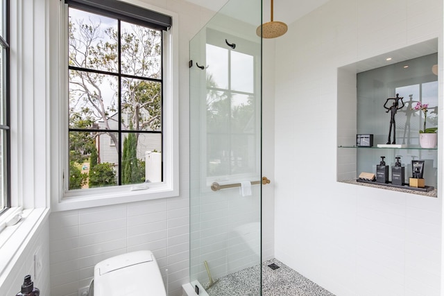 bathroom featuring walk in shower, toilet, and tile walls