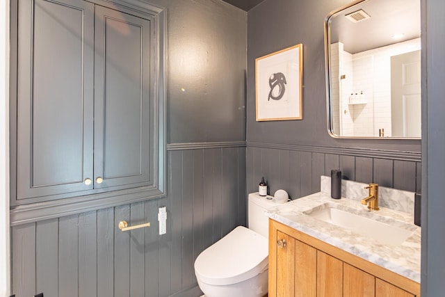 bathroom featuring wainscoting, toilet, and vanity
