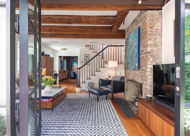 living room with light wood-style flooring, beam ceiling, stairs, and a fireplace