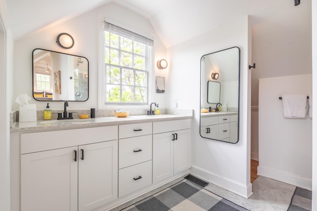 full bathroom featuring vaulted ceiling, double vanity, and baseboards