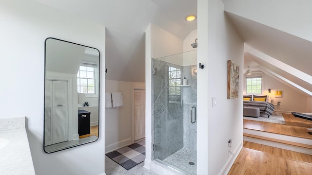 bathroom with vaulted ceiling, a closet, a shower stall, vanity, and wood finished floors