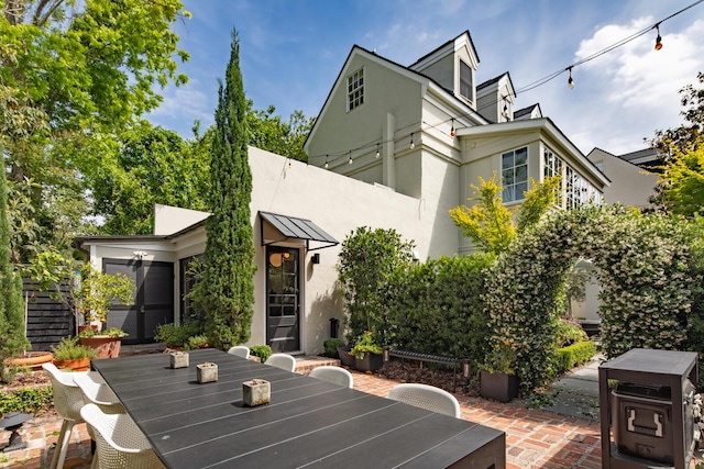 rear view of property with stucco siding, outdoor dining space, and a patio area