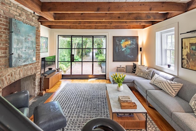 living room with beam ceiling, wood finished floors, and a fireplace