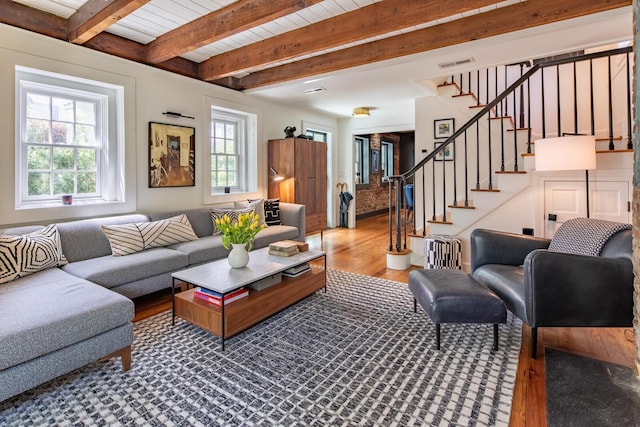 living room featuring wood finished floors, healthy amount of natural light, stairs, and beamed ceiling