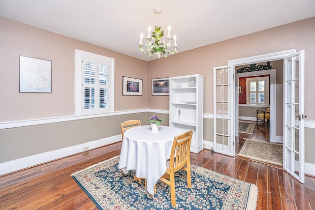 dining space featuring dark hardwood / wood-style flooring, french doors, and an inviting chandelier