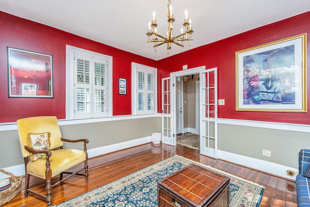 living area with wood-type flooring, an inviting chandelier, and french doors