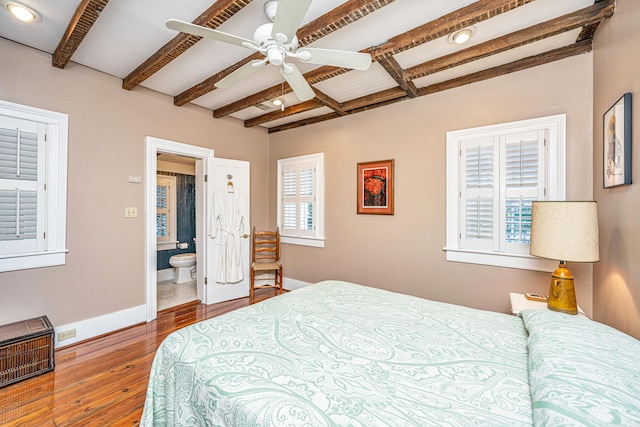 bedroom featuring multiple windows, connected bathroom, beamed ceiling, and ceiling fan