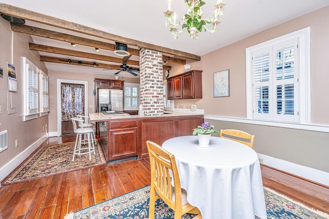 dining area featuring beamed ceiling, ceiling fan, and wood-type flooring