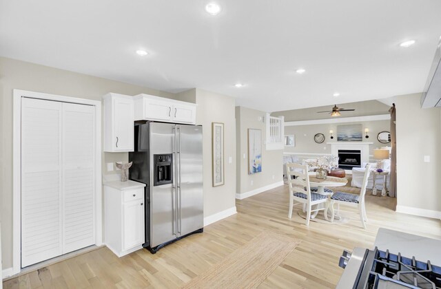 16 Oatly Cir, Charleston, SC 29414 - kitchen with stainless steel fridge, ceiling fan, a fireplace, light wood-style flooring, and white cabinetry