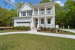 traditional home featuring a balcony, a porch, and a front yard