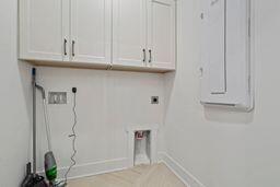 clothes washing area featuring cabinet space, electric dryer hookup, and baseboards