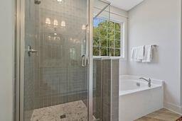 bathroom featuring a garden tub, a shower stall, baseboards, and wood finished floors