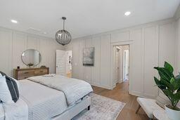 bedroom with recessed lighting, wood finished floors, and a decorative wall