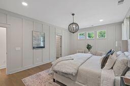 bedroom with recessed lighting, a decorative wall, and wood finished floors