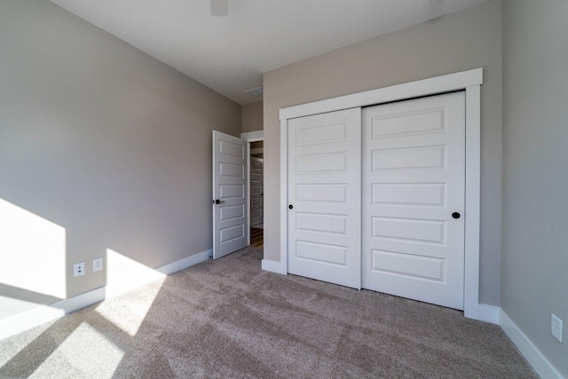 unfurnished bedroom featuring light colored carpet and a closet