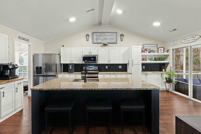 kitchen with white cabinetry, stainless steel appliances, a kitchen island with sink, and light stone counters