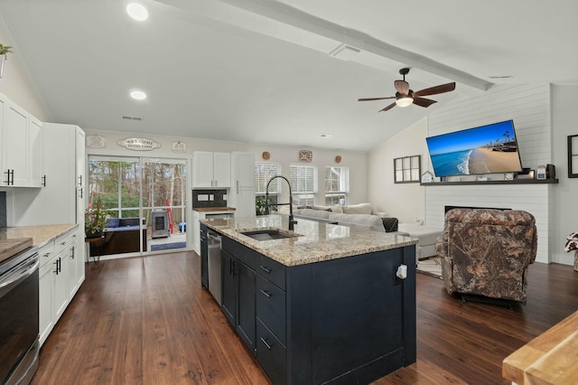 kitchen with sink, lofted ceiling with beams, white cabinets, and a center island with sink