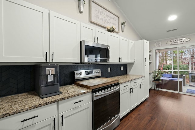 kitchen featuring dark hardwood / wood-style floors, white cabinetry, ornamental molding, stainless steel appliances, and light stone countertops