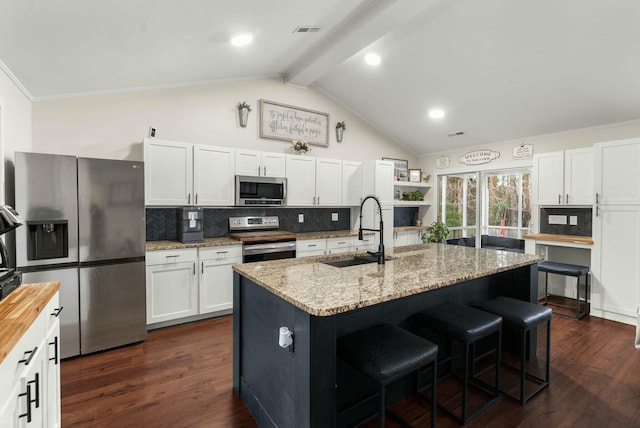 kitchen featuring stainless steel appliances, sink, white cabinets, and a kitchen island with sink