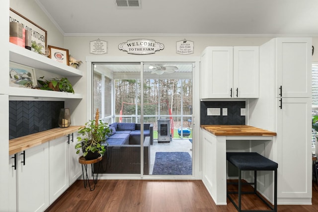 interior space featuring dark hardwood / wood-style flooring, butcher block countertops, crown molding, and white cabinets