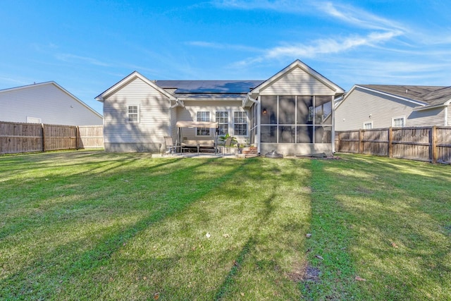 rear view of property featuring a lawn, a sunroom, solar panels, and a patio area