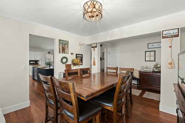 dining area with dark wood-type flooring, ornamental molding, an inviting chandelier, and sink