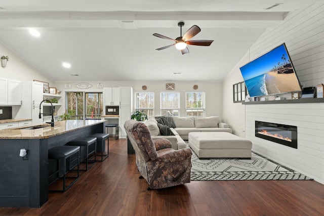 living room featuring dark wood-type flooring, a fireplace, sink, and beamed ceiling