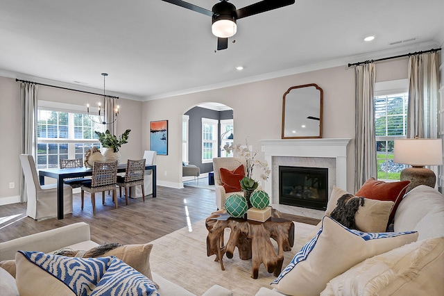 living area with arched walkways, plenty of natural light, visible vents, and crown molding