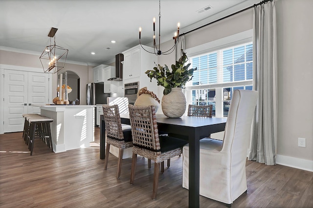 dining area featuring ornamental molding, dark wood-style flooring, visible vents, and a notable chandelier