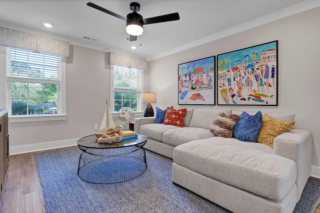 living area with baseboards, visible vents, a ceiling fan, wood finished floors, and crown molding