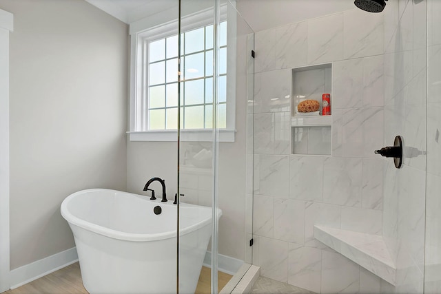 bathroom with a freestanding tub, a tile shower, baseboards, and wood finished floors