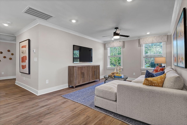 living area with crown molding, visible vents, ceiling fan, wood finished floors, and baseboards