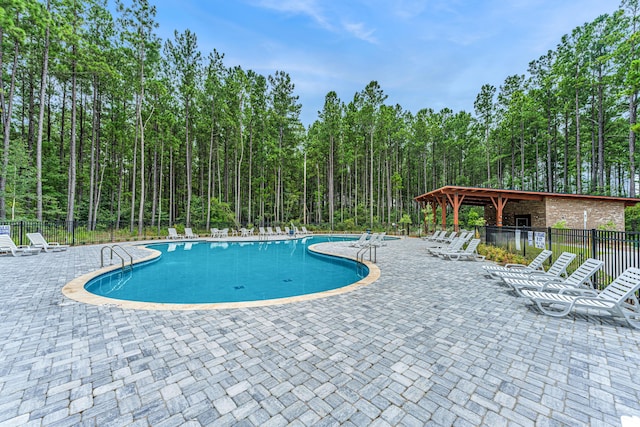 community pool with a patio area and fence