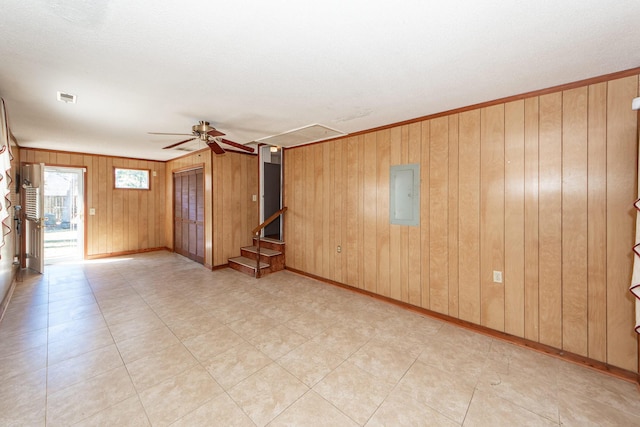 unfurnished living room with electric panel, baseboards, visible vents, ceiling fan, and stairs