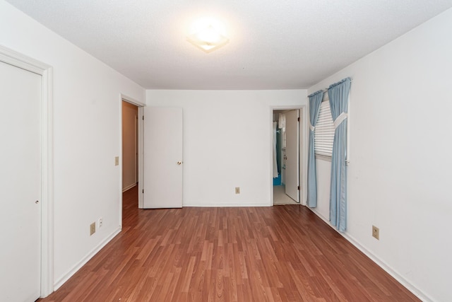 unfurnished bedroom with a closet, baseboards, and wood finished floors