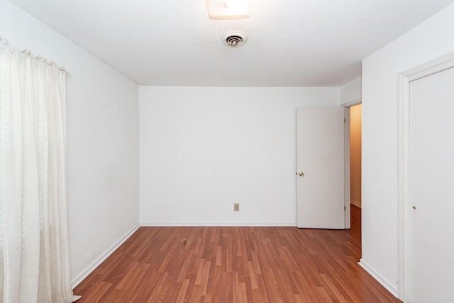 spare room with visible vents, light wood-style flooring, baseboards, and a textured ceiling