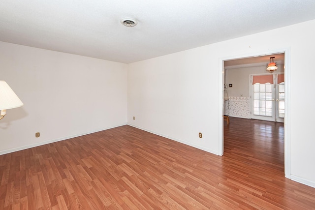 spare room featuring light wood-type flooring, baseboards, and visible vents