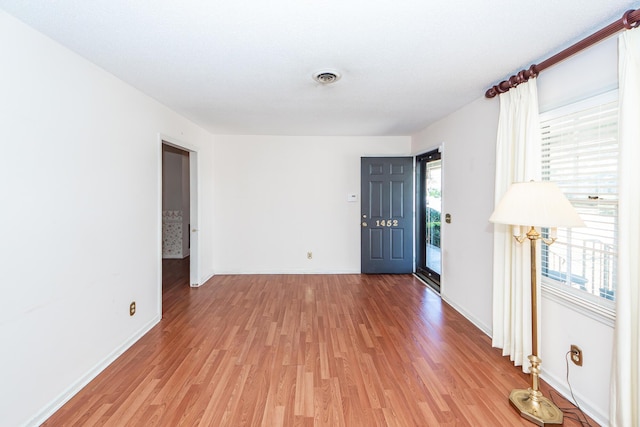 empty room with light wood-style floors, visible vents, and baseboards