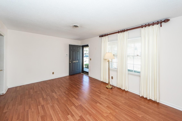 unfurnished room with plenty of natural light, light wood-style flooring, visible vents, and baseboards