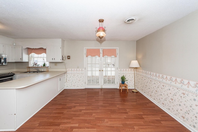 kitchen featuring wallpapered walls, appliances with stainless steel finishes, a sink, and wood finished floors