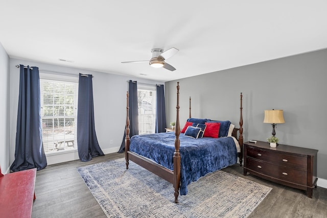 bedroom featuring multiple windows, ceiling fan, baseboards, and wood finished floors