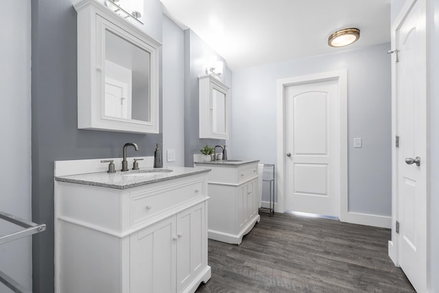 bathroom featuring a sink, baseboards, two vanities, and wood finished floors