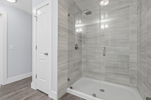 full bath featuring a stall shower, baseboards, and wood finished floors