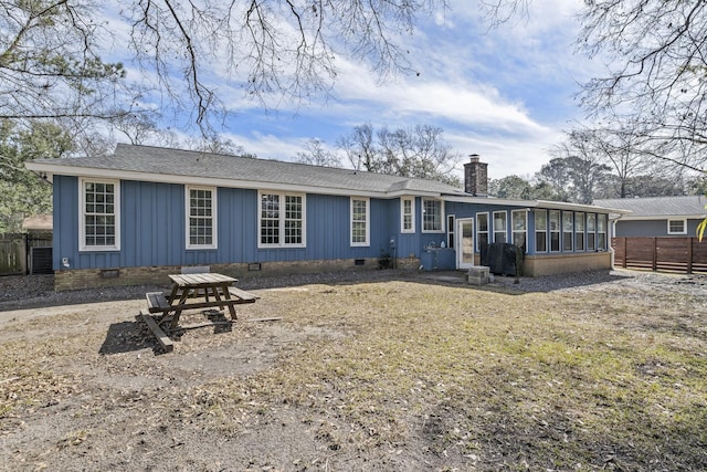 rear view of property featuring a sunroom, a chimney, crawl space, fence, and board and batten siding