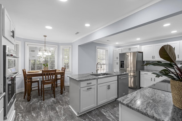 kitchen with dark stone counters, an island with sink, marble finish floor, stainless steel appliances, and a sink